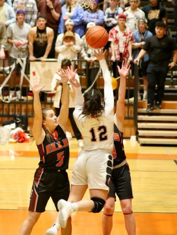 Kiana Meyer completes a jump shot while being blocked by two opponents.